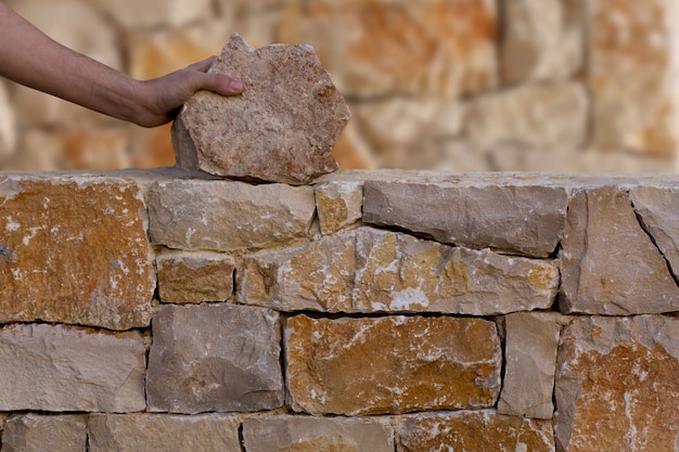 Foto mason manos trabajando en muro de mampostería de piedra