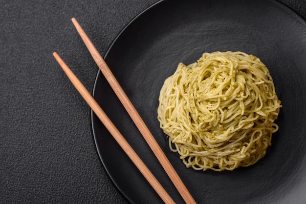 Massa Capellini ou macarrão com molho pesto, sal e especiarias sobre um fundo escuro de concreto