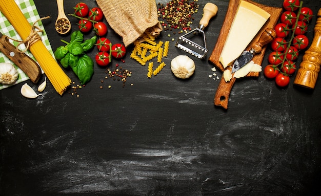 Massa crua com tomates e queijo em uma tabela preta