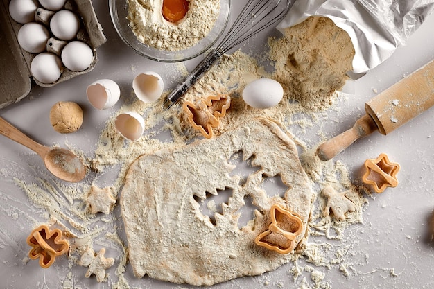 Massa crua de conceito de cozimento para cortadores de farinha de ovos de biscoito em forma de estrela e borboleta em uma mesa branca Vista superior