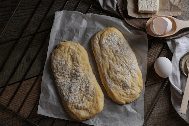 Massa crua para ciabatta e farinha na mesa de madeira plana