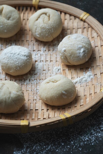 Massa crua para fazer pães asiáticos na tradicional bandeja de bambu. Processo de cozimento caseiro. Fechar-se.