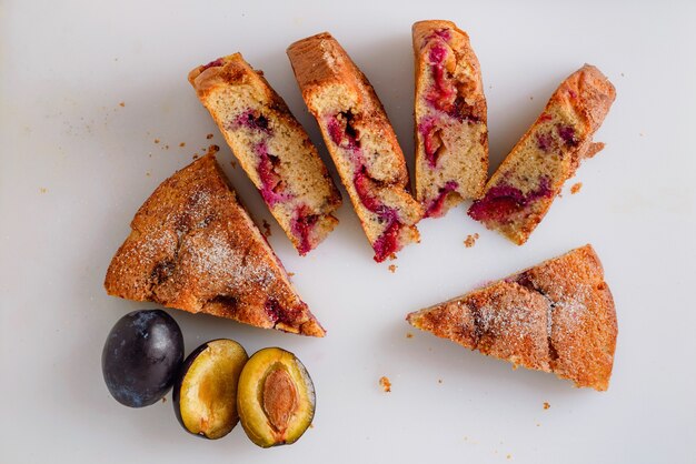 Massa de ameixa cortada em pedaços, delicioso bolo de ameixa em quadro branco com decoração de ameixas frescas.