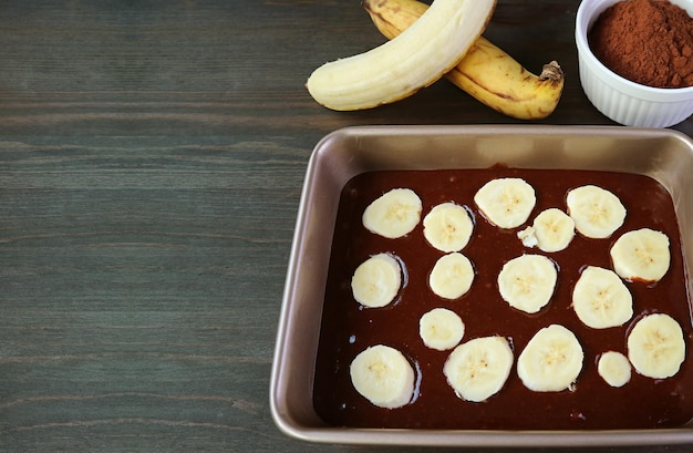 Foto massa de bolo de banana de chocolate escuro na forma de bolo antes de assar na mesa de madeira