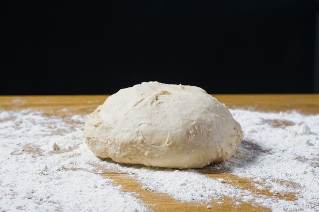 Massa de fermento em uma mesa de madeira polvilhada.