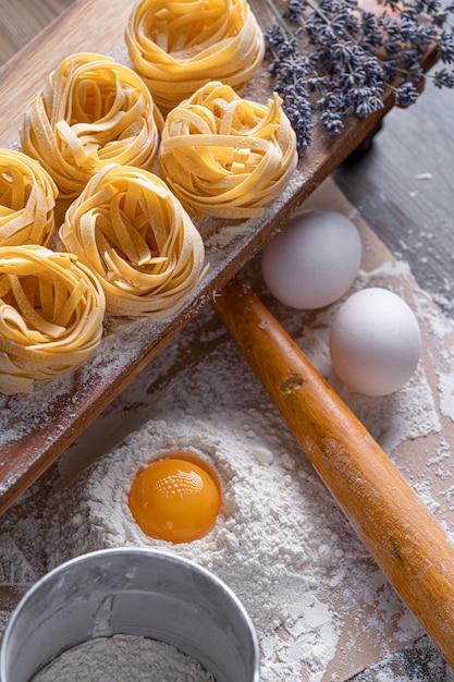 Massa de fettuccine caseira dobrada em forma de ninho Cozinha caseira com ingredientes para massa de fettuccine italiana tradicional caseira