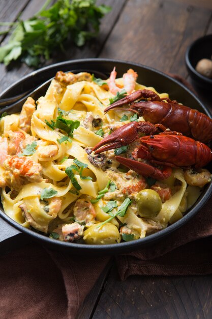 Massa de fettuccine de frutos do mar com lagostins, polvos, na panela de pedra. Prato Gourmet