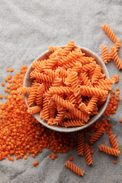 Massa de lentilha vermelha fusilli sobre um fundo têxtil cinza