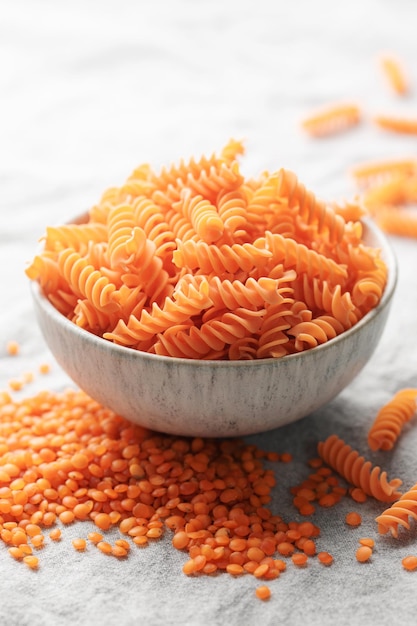 Massa de lentilha vermelha fusilli sobre um fundo têxtil cinza