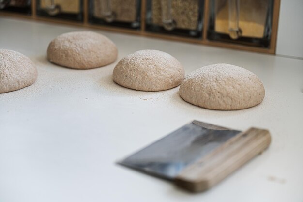 Massa de pão de fermento caseiro subindo no balcão de cozinha polvilhado de farinha com um cortador ao lado deles