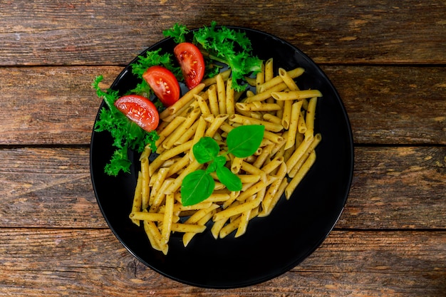 Massa de Penne com molho do pesto na placa em um fundo de madeira. vista do topo