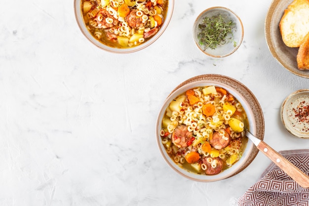 Foto massa de tubetti de salsicha defumada ou orzo sopa tradicional italiana com macarrão e legumes da estação