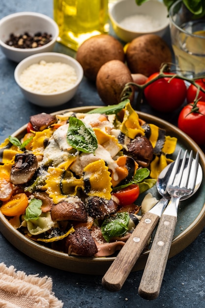 Massa farfalle com cogumelos, manjericão, tomate e molho de natas. cozinha tradicional italiana. comida mediterrânea