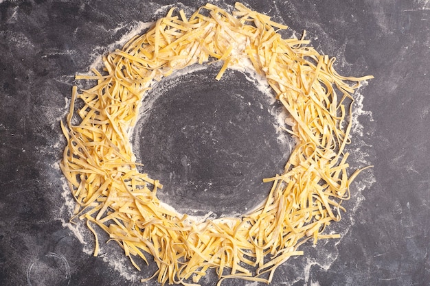 Massa fresca com fundo de massa italiana caseira com fettuccine cozinhada na cozinha da casa com ovos frescos e farinha em um fundo de madeira foto de alta qualidade do conceito de cozinha e comida italiana