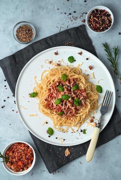 Massa italiana à bolonhesa com manjericão e nozes em um fundo cinza.