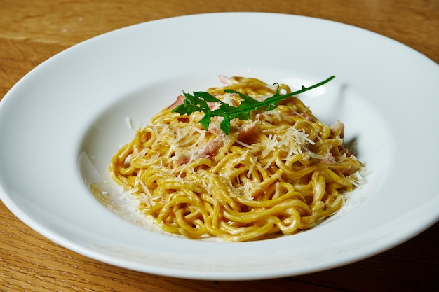 Massa italiana caseira em molho cremoso, bacon e parmesão em um prato branco. Cozinha italiana .. Mesa de fotos de comida saborosa