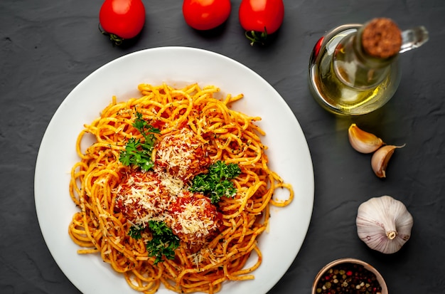 Massa italiana com molho de tomate e almôndegas em um prato sobre um fundo de pedra