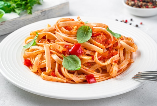 Massa italiana com tomate e manjericão closeup em um fundo cinza claro