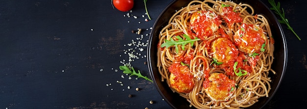 Massa italiana. Espaguete com almôndegas e queijo parmesão em chapa preta na mesa de madeira rústica escura. Jantar. Vista do topo. Conceito de comida lenta