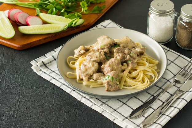 Massa italiana integral com fígado de frango assado e cebola servida em um prato com fundo de mármore.