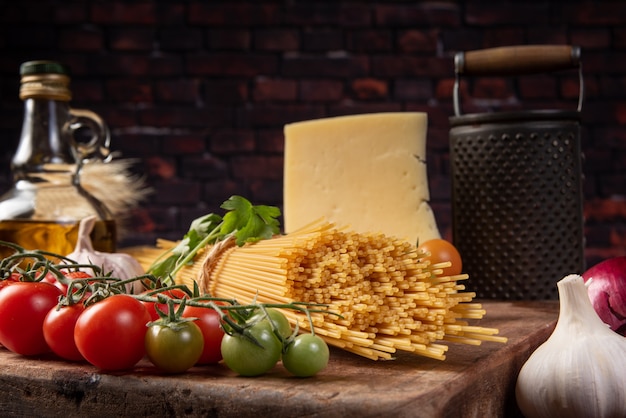 Foto massa italiana (macarrão), tomate, azeite, queijo e temperos em madeira rústica