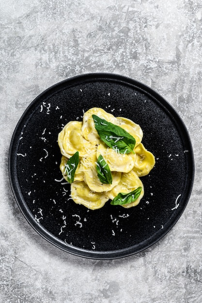 Foto massa italiana ravioli com queijo e manjericão. fundo cinza. vista do topo