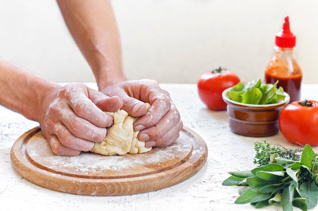 Massa. O processo de fazer pizza. Ingredientes para pizza. Amassar massa com as mãos