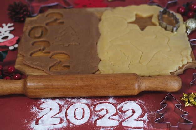 Foto massa para fazer biscoitos caseiros de gengibre em uma placa de madeira sobre um fundo vermelhonatal