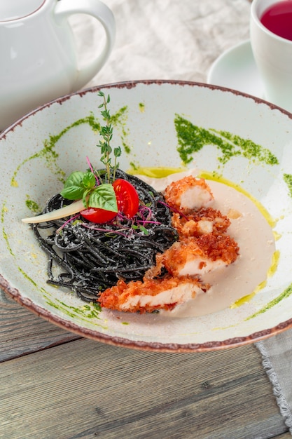 Massa tagliolini preto fresco com frango em ervas na rúcula e tomate