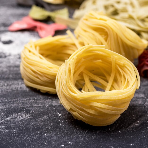 Massa tipo Tagliatelli italiana não cozida com fundo cinza quadrado comida italiana