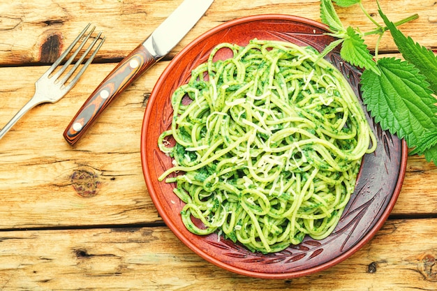 Massa tradicional italiana com molho de erva de urtiga. Massa verde na mesa de madeira.