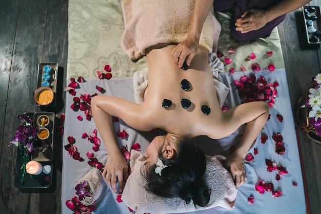 Massage- und Spa-entspannende Behandlung des Bürosyndroms mit traditionellem Thai-Massagestil mit heißem Stein Asain-Masseurin, die eine Massage durchführt, behandeln Rückenschmerzen, Armschmerzen, Stress für Frauen, die von der Arbeit müde sind