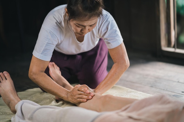 Foto massage- und spa-entspannende behandlung des bürosyndroms mit traditionellem thai-massagestil mit heißem stein asain-masseurin, die fußmassagen durchführt, behandelt stress für frauen