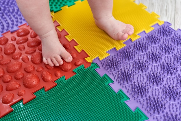 Massageador de pés Kid andando em uma esteira de massagem ortopédica Tratamento e prevenção de pés chatos em crianças