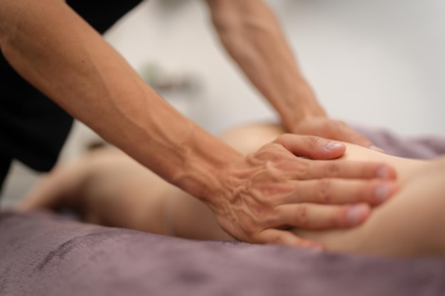 Foto massageiro fazendo uma massagem profunda das pernas no spa