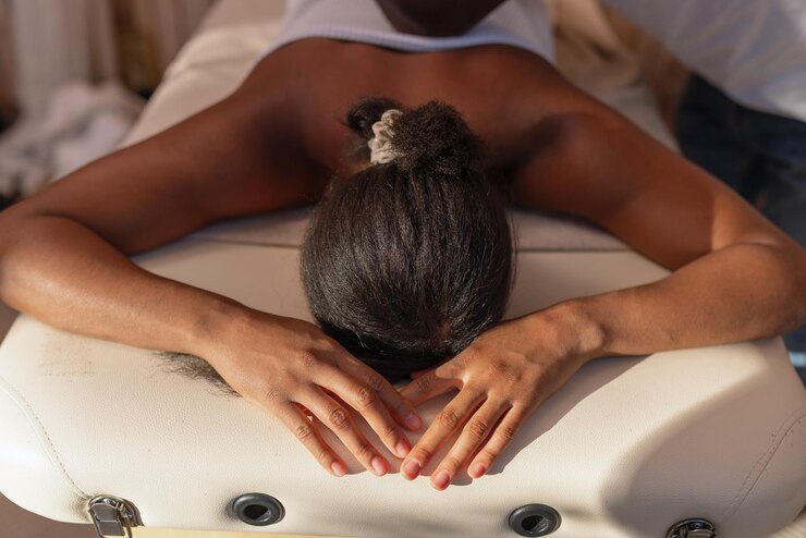 Foto massageiro profissional afro-americano a dar uma massagem relaxante a uma cliente feminina. um luxo.