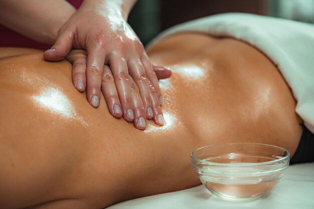 Foto massagem com óleo de massagem mãos de uma massagista massagem massagem de uma cliente feminina