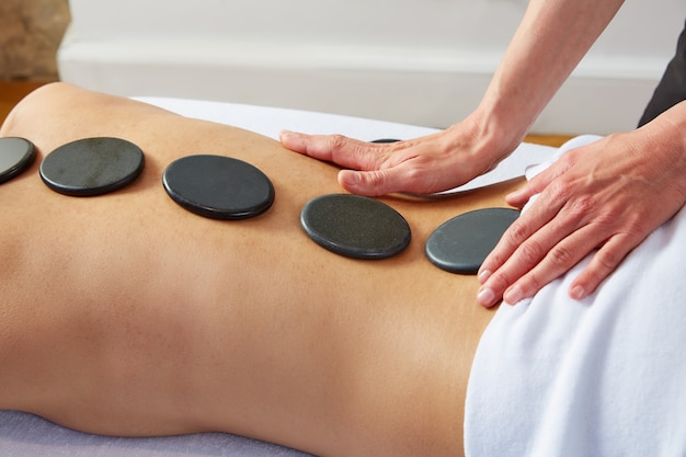 Massagem com pedras quentes na mulher fisioterapeuta