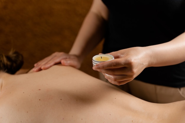 Massagem corporal com cera à base de velas. Procedimento de spa de beleza. Massagem tailandesa com cera quente.