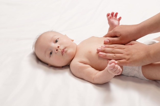 Massagem de barriga de bebê, close-up das mãos de uma mulher