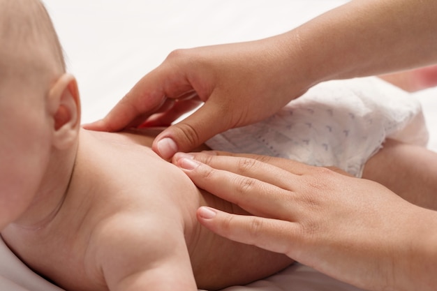 Massagem de bebê, close-up com as mãos nas costas do bebê