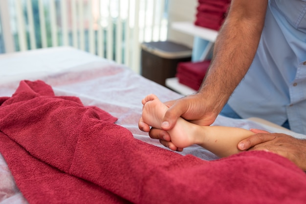 Foto massagem de bem-estar para crianças close up das mãos do massagista fisioterapeuta trabalhando com o paciente