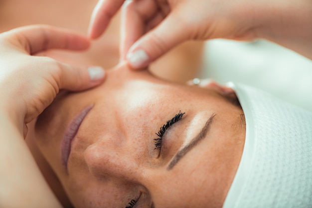 Massagem de lifting facial mulher linda recebendo massagem de face lifting em um salão de beleza