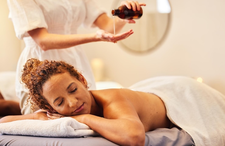 Foto massagem de luxo spa e mulher com óleo essencial recebendo massagem nas costas para bem-estar no salão de beleza beleza de saúde e mulher negra com massoterapeuta para relaxamento, alívio do estresse e cuidados com o corpo