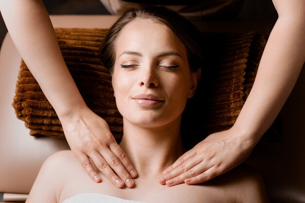 Massagem de pescoço e rosto no spa. Massagista está fazendo tratamentos de beleza facial para uma atraente modelo feminina. Relaxamento.