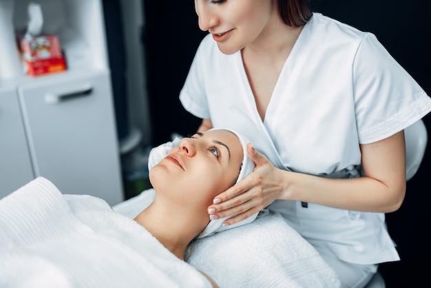 Massagem facial em paciente, clínica de cosmetologia