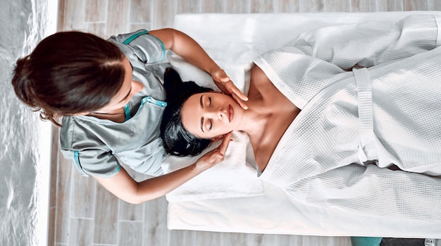 Massagem facial jovem mulher recebendo tratamento de spa vista superior