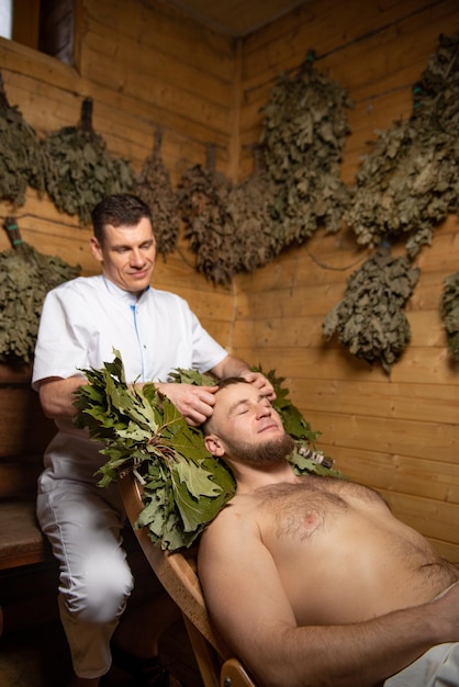 Massagem facial para um homem em um banho Um atendente masculino realiza procedimentos para um cliente na sauna Massagem relaxante