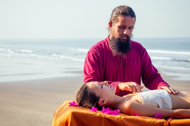 Massagem relaxante ayurvédica, mulher de saúde no salão spa recebendo massagem na praia de férias.