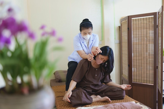 Massagem spa tratamento relaxante síndrome do escritório massagem tailandesa tradicional mulher asiática sênior medicina tradicional tailandesa usando máscara de massagem tratar dor nas costas dor no braço dor no pé pés e estresse